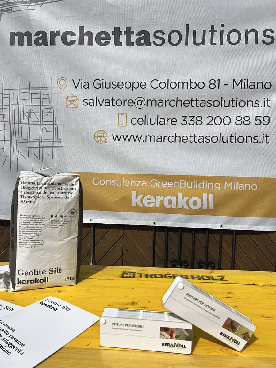 Marchetta Solutions, consulenza edilizia green Building Milano, cartellone bianco con recapiti e un tavolo con sopra delle brochure e un sacco di geolite silt di kerakoll
